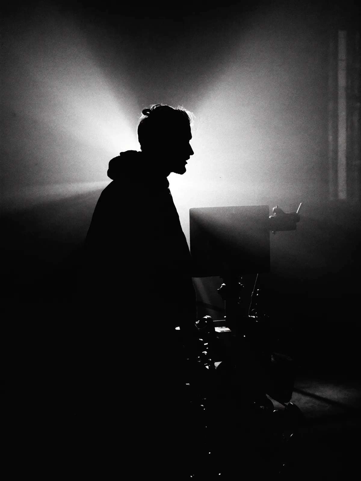 Silhouette d'un chef opérateur derrière une caméra de cinéma, noir et blanc
